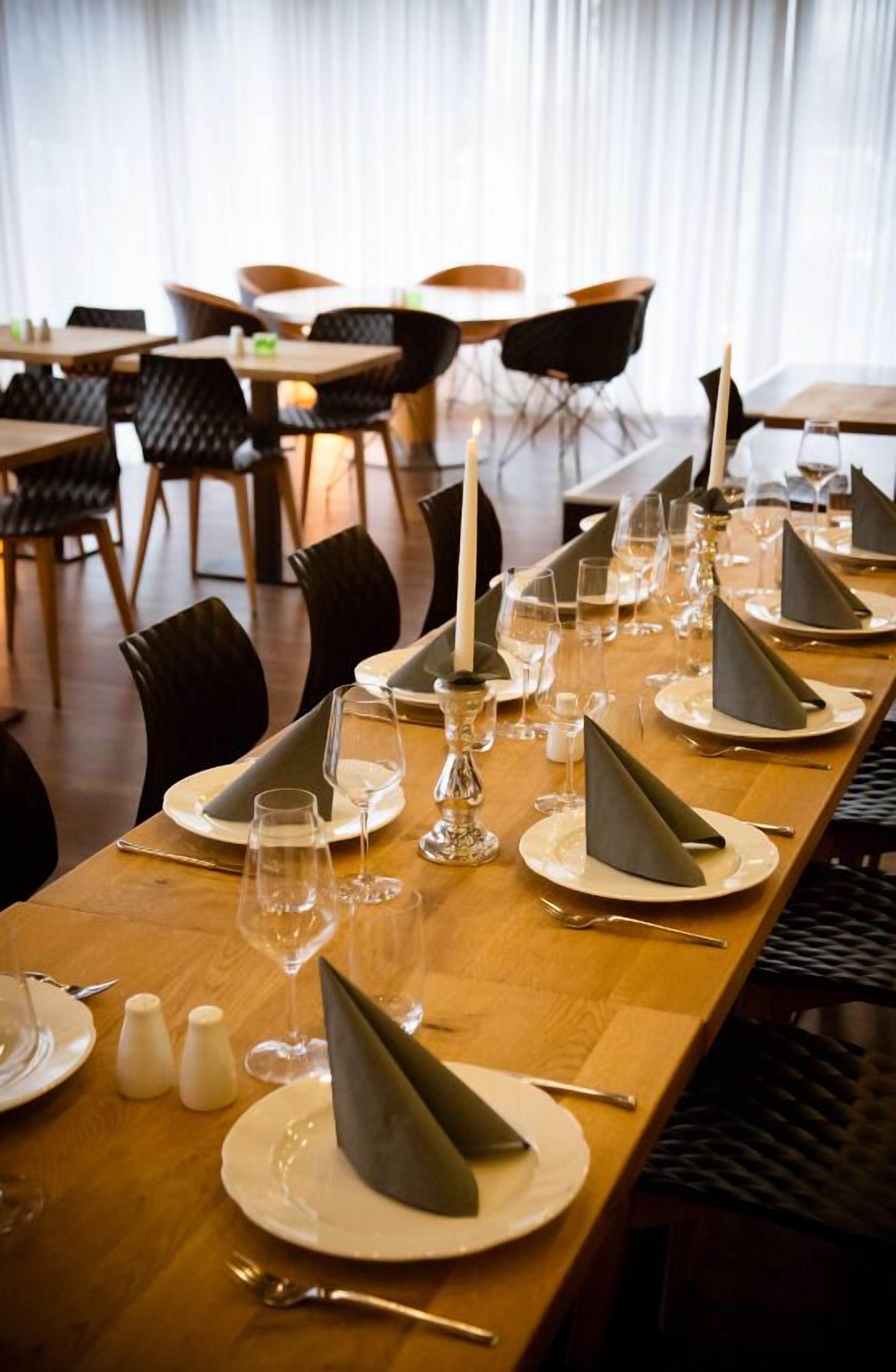 A dining area with a long wooden table set for a meal, complete with plates, glasses, and napkins.