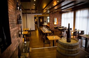 A restaurant with brick walls, wooden tables, and a bar area with wine bottles. - Rheinhessen Inn (Woerrstadt)