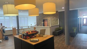 A modern kitchen area with a central island, wooden flooring, and pendant lighting. - Rheinhessen Inn (Woerrstadt)