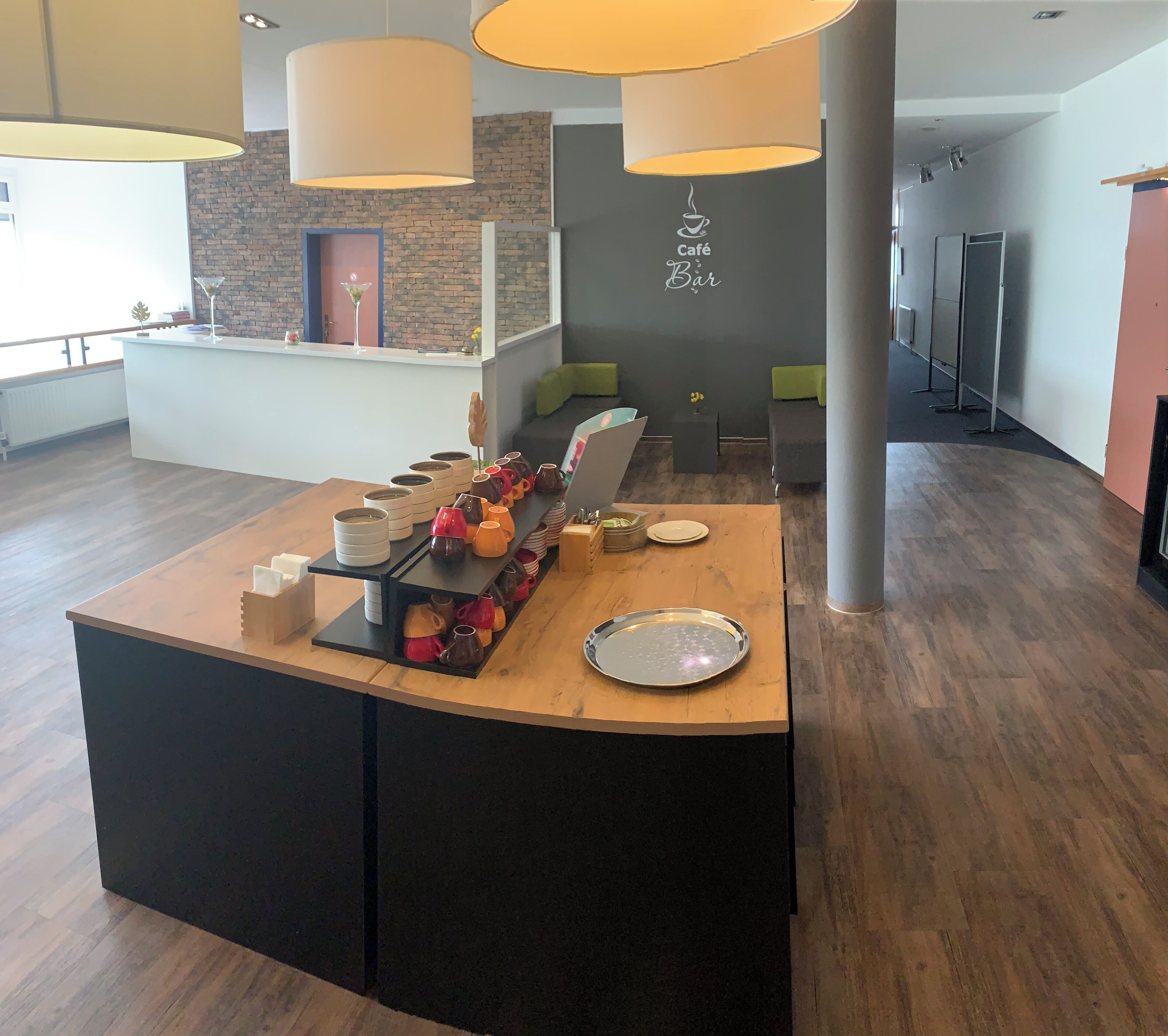 A modern reception area with a wooden counter displaying various ceramic mugs and plates.
