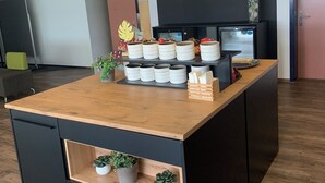 A reception area with a wooden counter, a chalkboard with 'Welcome' and 'Bienvenue' written, a coffee station, and a refrigerator. - Rheinhessen Inn (Woerrstadt)