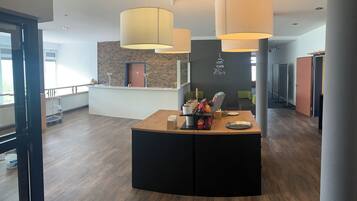Un interior moderno con mostrador de recepción, suelo de madera e iluminación colgante.
