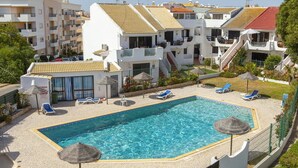 A rooftop swimming pool with lounge chairs and umbrellas, surrounded by apartment buildings. - C06 - Porto do Mos 3 bed Townhouse by DreamAlgarve (Lagos)