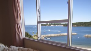 A room with a view of the sea, a wicker chair, and a round wicker table. - Hotel Hana (Shima)