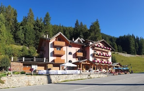 A multi-story hotel with balconies, a stone facade, and a mountain backdrop. - Hotel La Roccia (Ponte di Legno)
