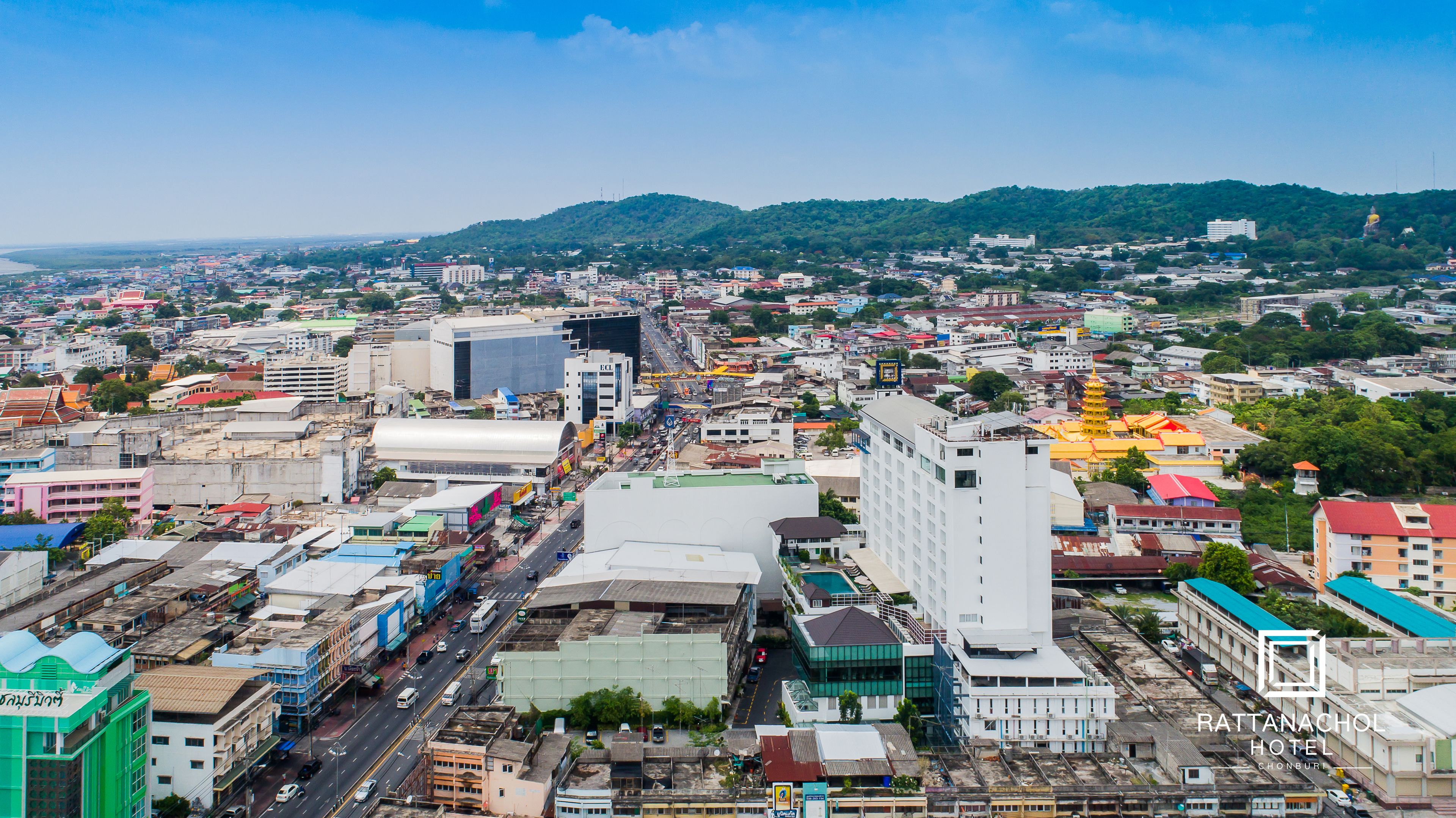 A cityscape with a prominent white building with a modern design, a busy street with vehicles, and a large yellow pagoda-like structure in the distance.