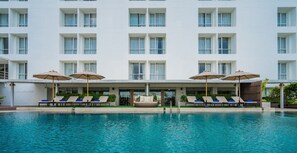 Un hotel con piscina, tumbonas y sombrillas.