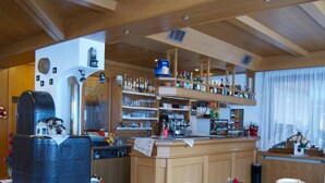 Una cocina acogedora con armarios de madera, una isla central y una zona de bar con estantes llenos de botellas y vasos.