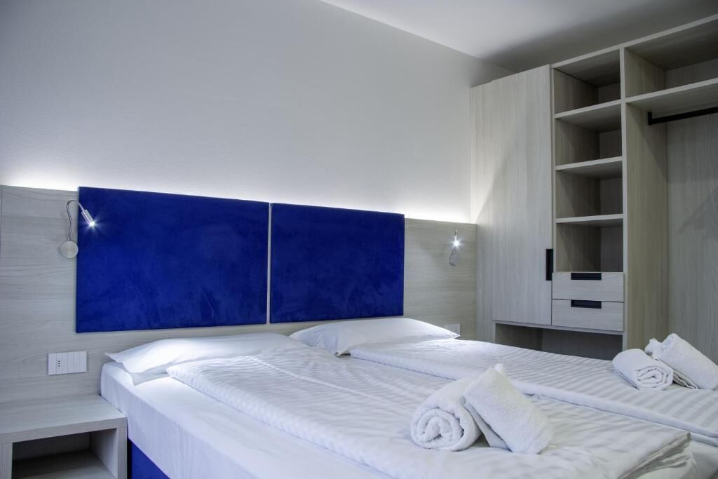 A hotel room with a large bed, a wardrobe, and a nightstand.