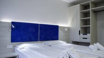 A hotel room with a large bed, a wardrobe, and a nightstand.