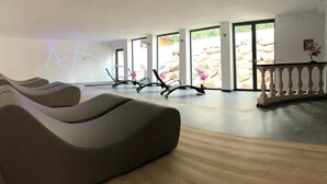 Un moderno espacio de spa con un ventanal amplio, una zona de relajación con bancos e instalaciones de iluminación decorativa.