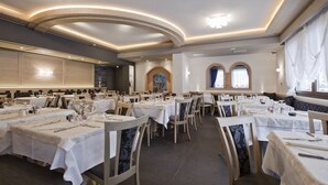 Un comedor amplio con varias mesas y sillas, que destaca por un diseño moderno en el techo y grandes ventanales.