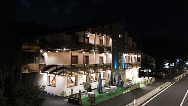Un hotel de varios pisos con terraza exterior y fachada bien iluminada.