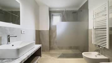 Une salle de bain moderne avec un grand miroir, un lavabo sur pied, un bidet et un espace douche.