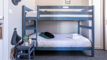 Camera con letto a castello e un piccolo tavolino accanto, con un telefono, bottiglie d'acqua e una tazza.