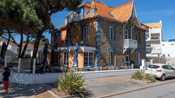 Un edificio con fachada de piedra, varios balcones y techo de tejas.