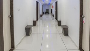 Un couloir propre et bien éclairé, avec des murs blancs, des portes en bois foncé et un éclairage bleu sous les meubles.