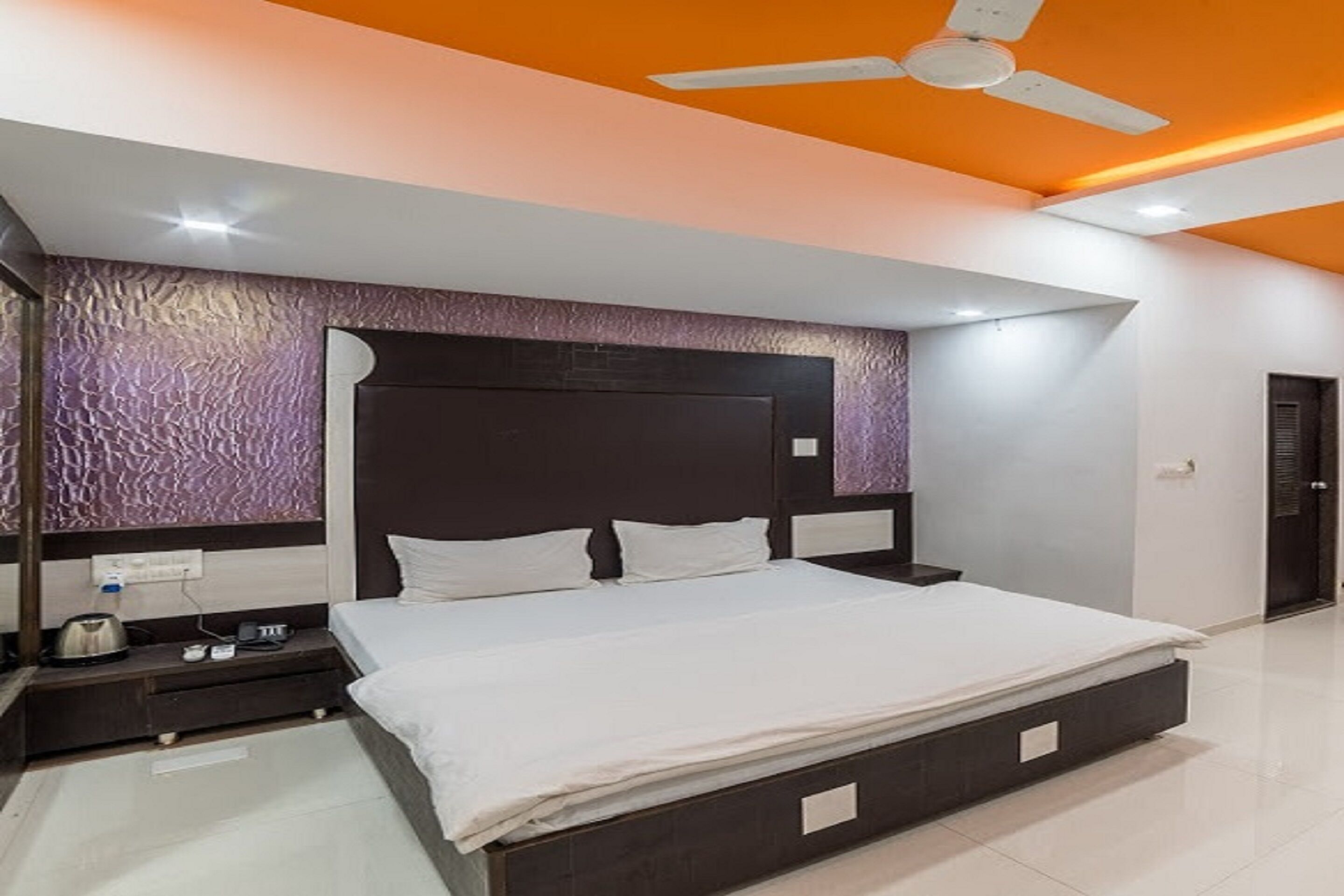 A modern bedroom with a large bed, a ceiling fan, and a textured wall.