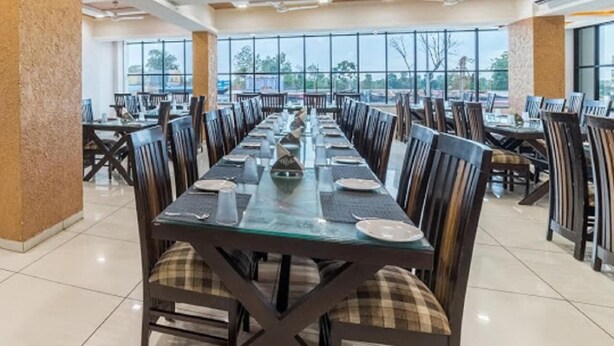 Un vaste espace dédié à la salle à manger, avec de longues tables et des chaises, de grandes fenêtres et un design moderne au niveau du plafond.