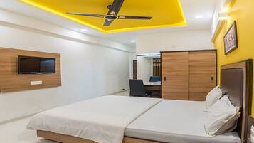 Een hotelkamer met een bed, een bureau, een stoel, een telefoon en een plafondventilator.