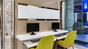 Un espacio de oficina moderno con dos escritorios, cada uno con un monitor de computadora, teclado y una silla verde.