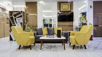 Una sala de estar moderna con un sofá, dos sillones amarillos, una mesa de centro y plantas decorativas.