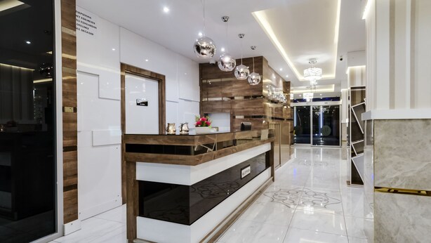 Una zona de recepción con mostrador de madera, vitrina de cristal y una lámpara de araña moderna.