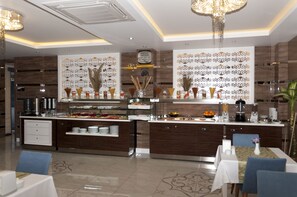Comedor moderno de hotel con estación de buffet, un reloj y paneles decorativos en la pared.
