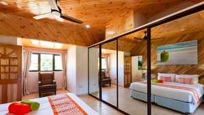 Habitación de hotel con una cama grande, una silla, un escritorio y un ventanal corredero que da a un balcón.
