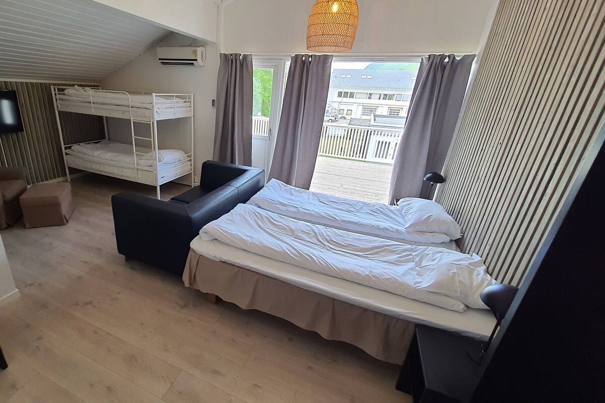 Een compacte hotelkamer met een stapelbed, een slaapbank, een bureau en een televisie.