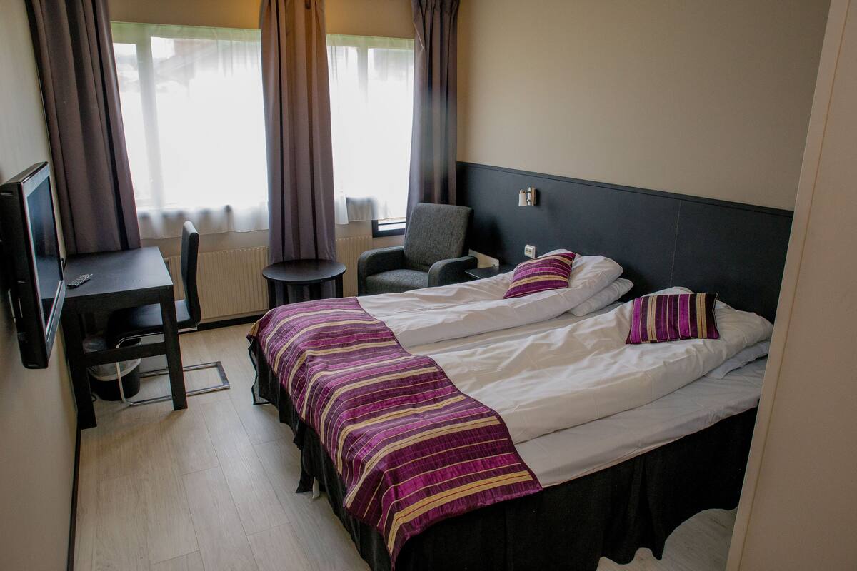 Een hotelkamer met een bed, bureau, stoel en televisie.