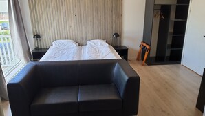 A modern bedroom with a large bed, a black leather sofa, and a wooden wardrobe. - Systra Hotel Apartments Sjøholt (Ålesund)