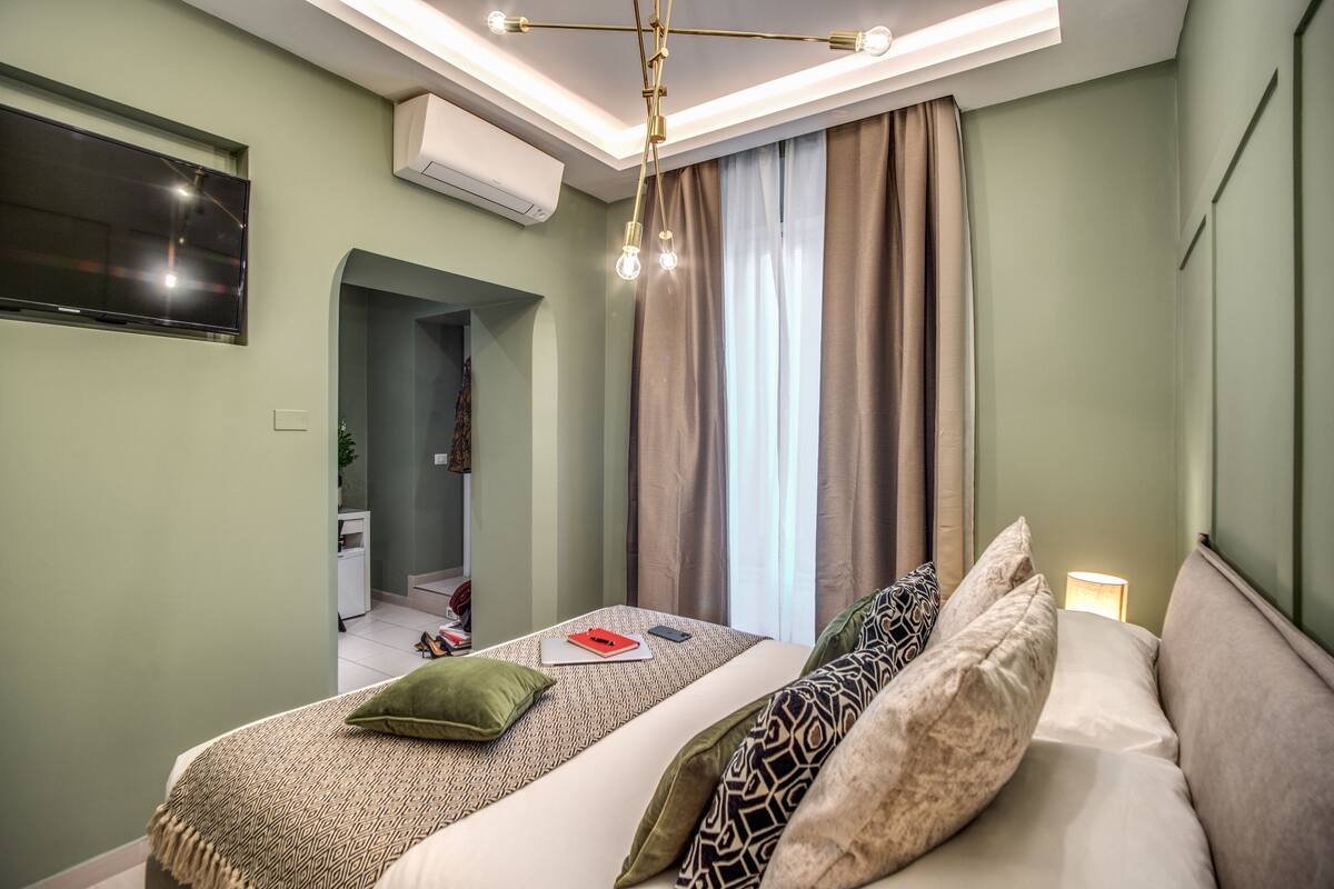 A modern bedroom with a bed, a TV, and a ceiling light fixture.