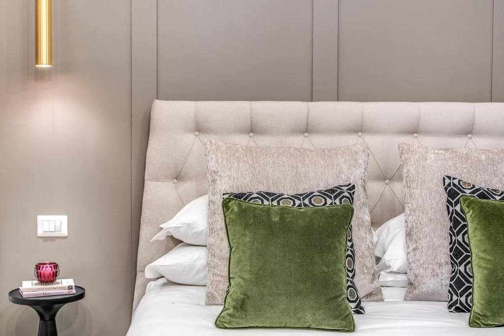 A bedroom with a tufted headboard, a bedside table with a lamp, and decorative pillows.