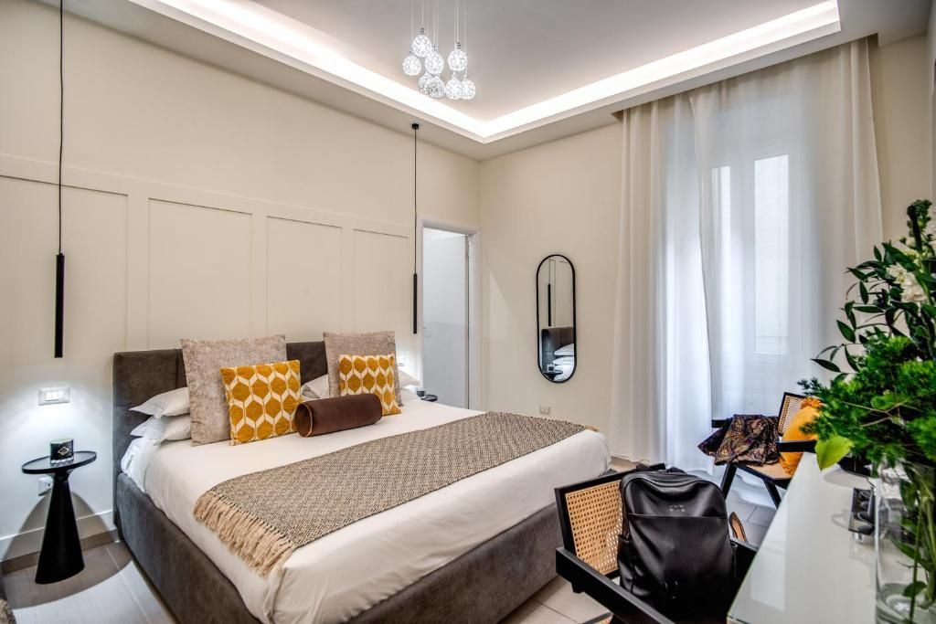 A modern bedroom with a large bed, bedside tables, a mirror, and a desk with a chair.