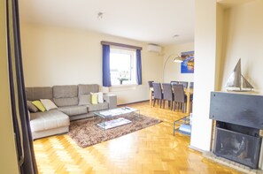 Una sala de estar con sofá, mesa de centro y chimenea. Hay un comedor con sillas y una mesa.