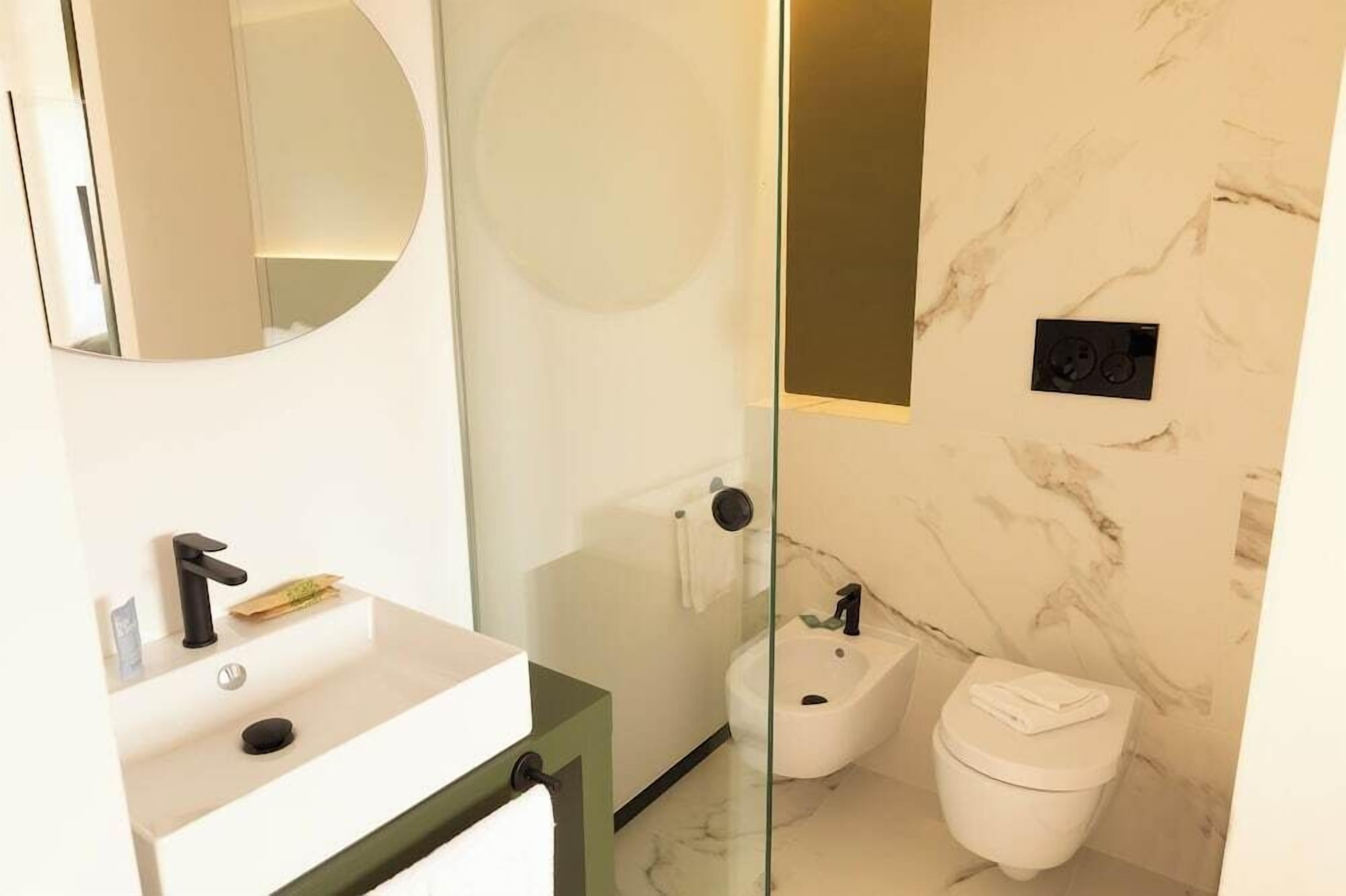 Une salle de bain moderne avec un lavabo blanc, un miroir, un bidet et des toilettes.