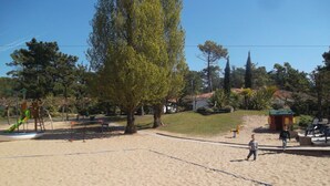 A sandy beach area with playground equipment, including a slide and swings, surrounded by trees and a small building. - le Hameau de l'Océan (Saint-Hilaire-de-Riez)