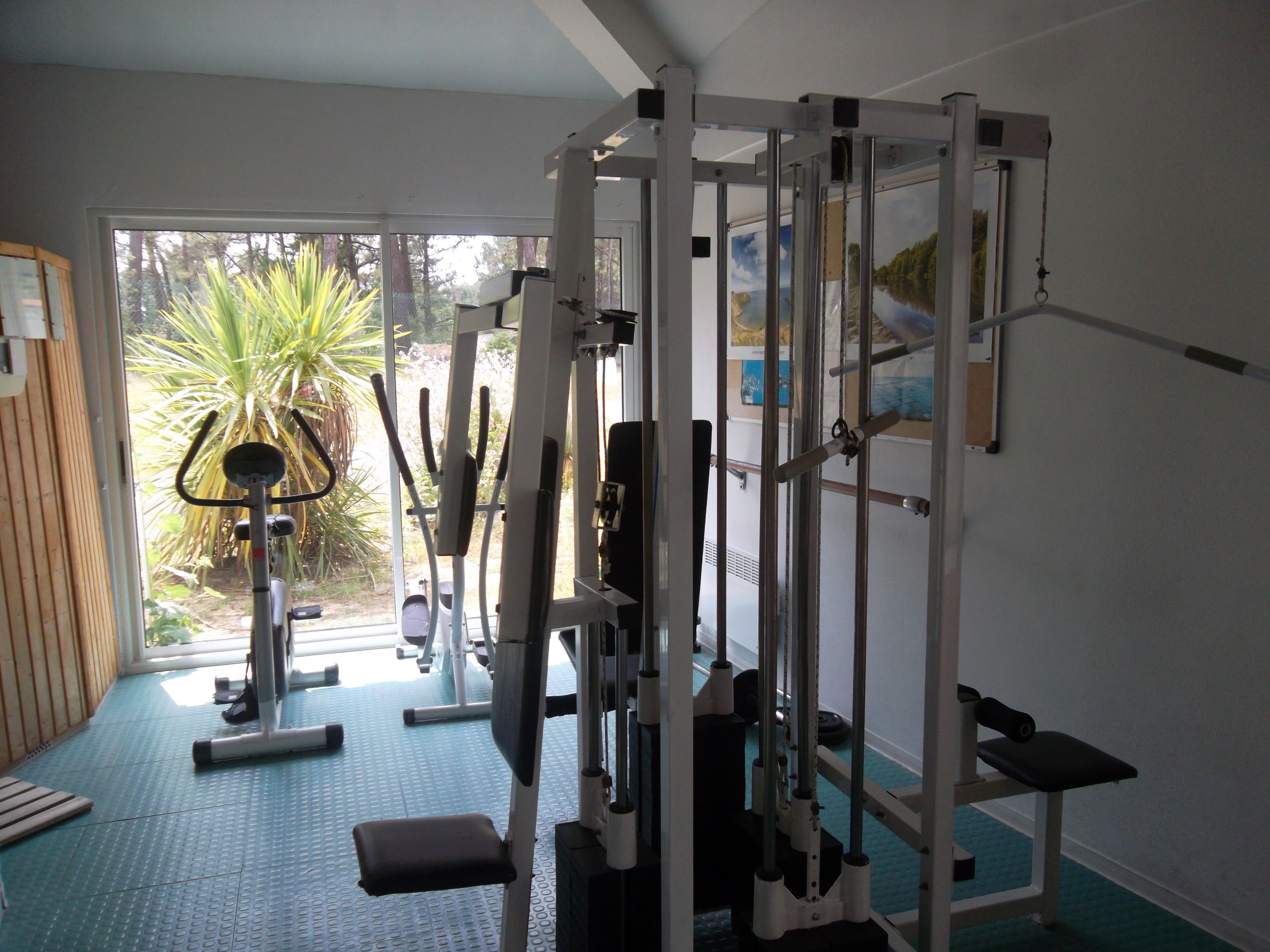 Une salle de sport équipée de matériel d’exercice, d’un banc et offrant une vue sur l’extérieur.