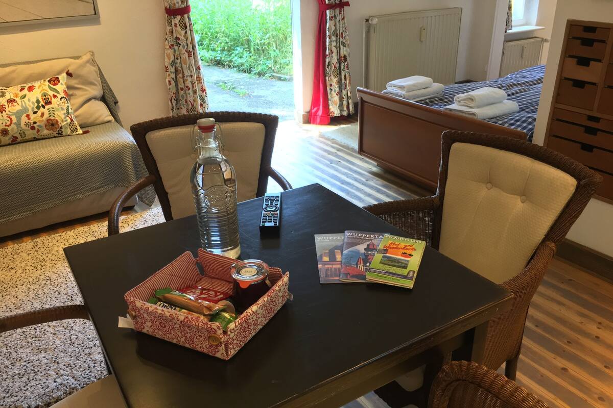 Ein Hotelzimmer mit Esstisch, Stühlen, einer Couch, einem Bett und Blick auf den Garten.
