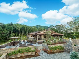 Un amplio patio exterior con varias zonas de estar y un jardín con muro de piedra.