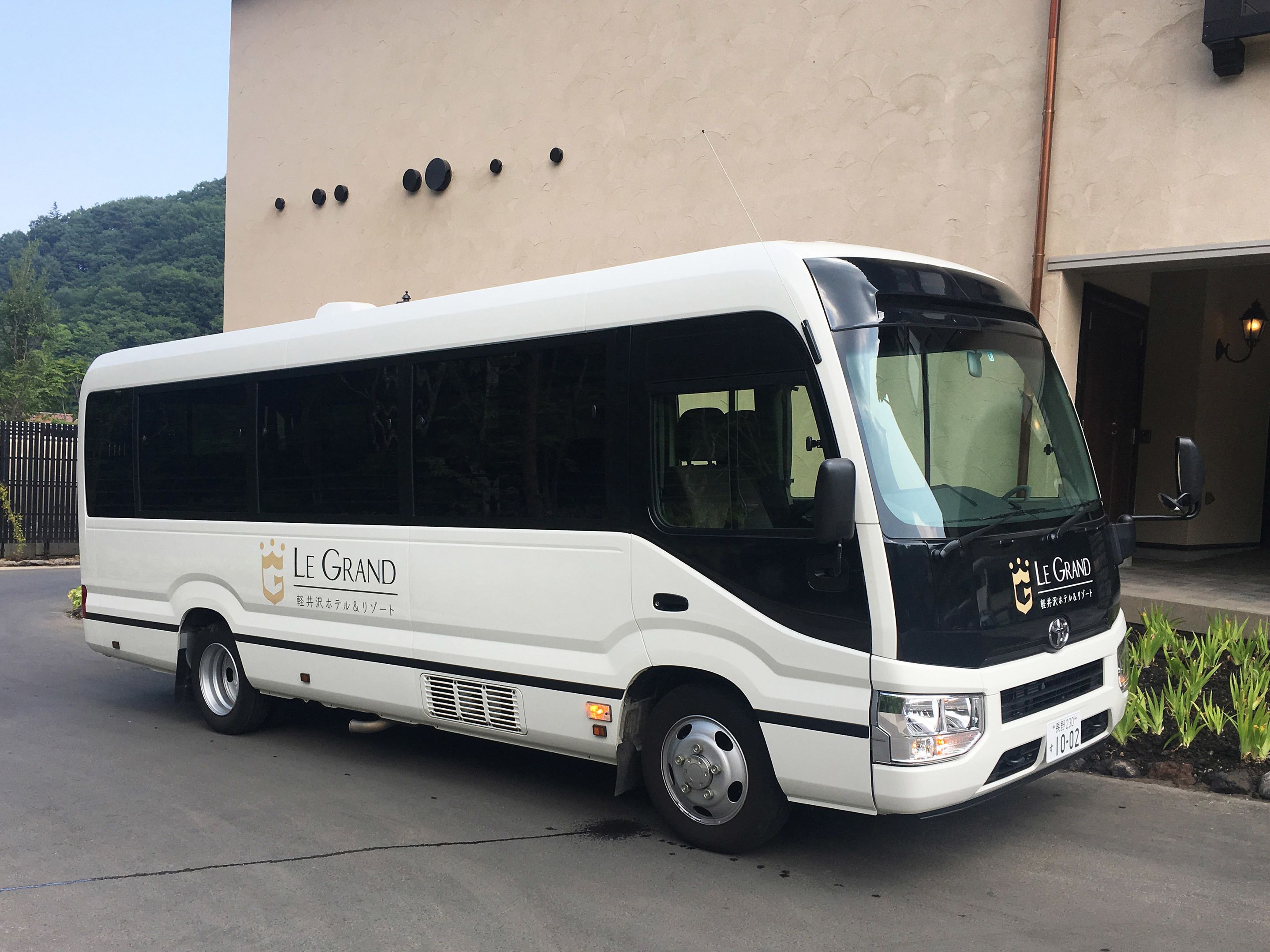A white and black bus with "Le Grand" branding parked in front of a building.