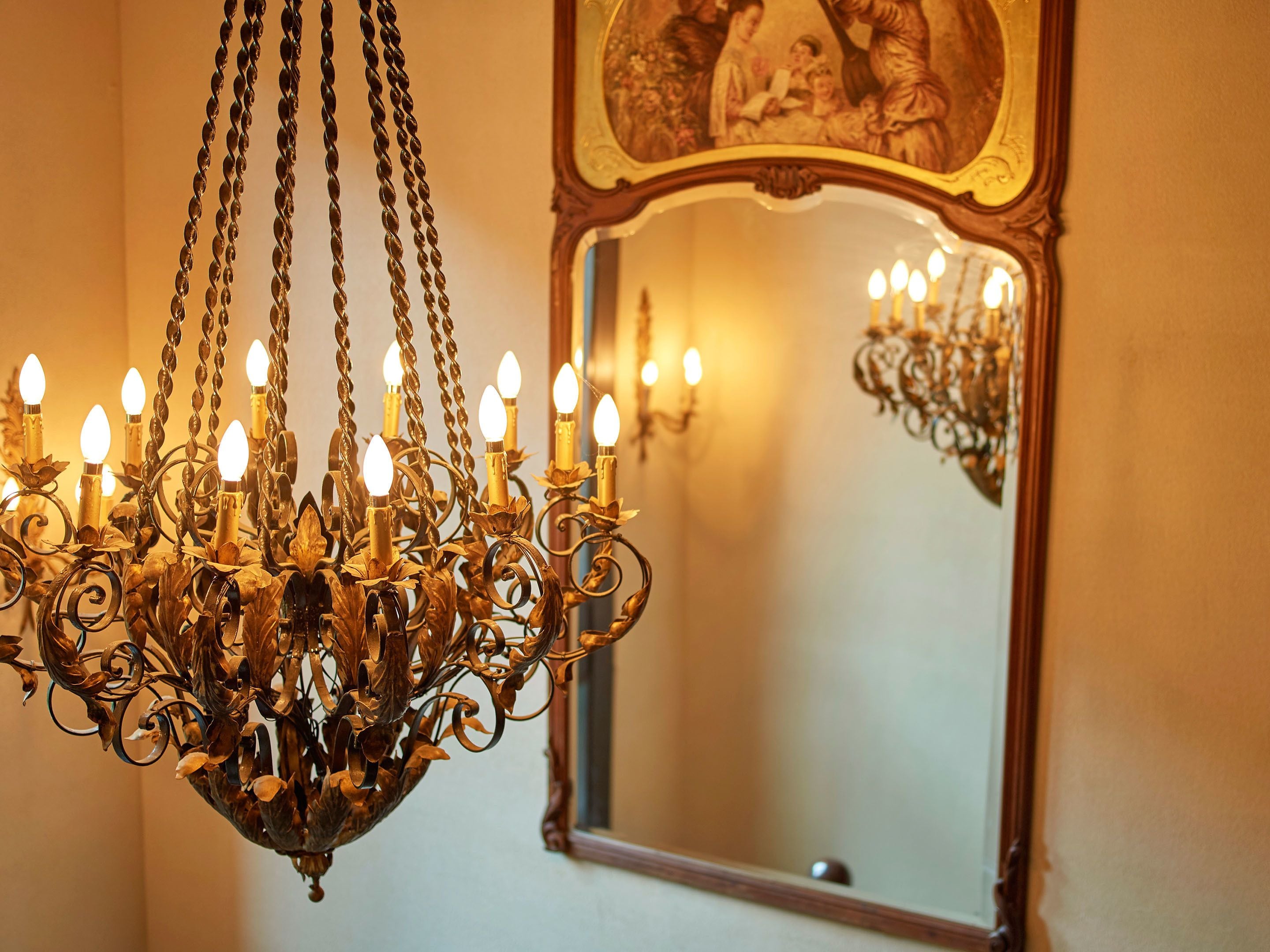 A chandelier with multiple light fixtures and a mirror with a decorative frame.