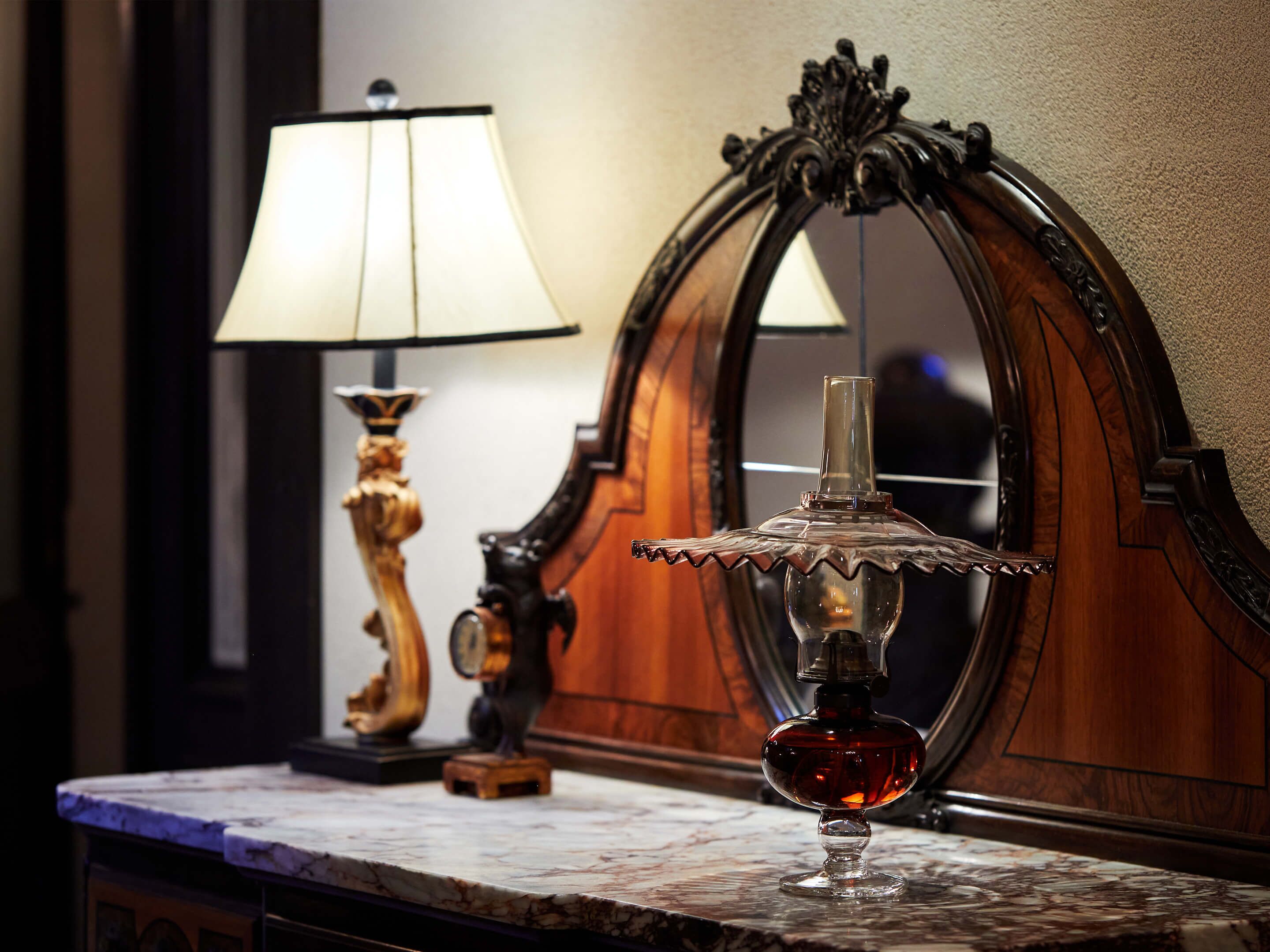 A marble countertop with a glass decanter and a lamp.