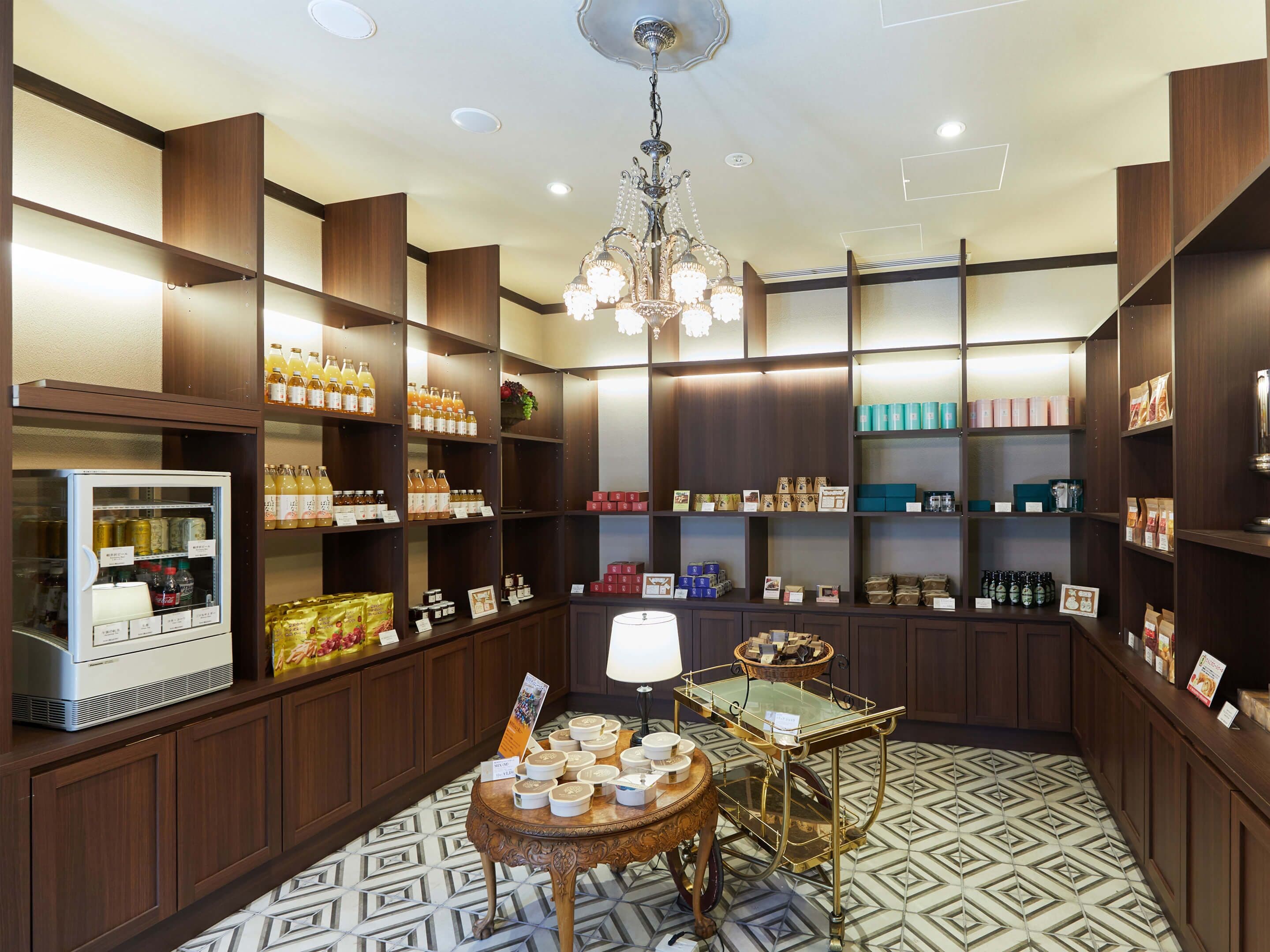 A well-organized retail space with shelves stocked with various products, a display counter with items, and a chandelier.