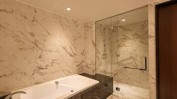 A modern bathroom with a marble vanity, a glass-enclosed shower, and a large bathtub.