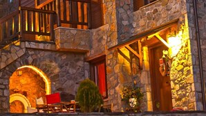 A stone and wood lodge with a porch and a fireplace. - Efharis Filoxenon (Sikyona)