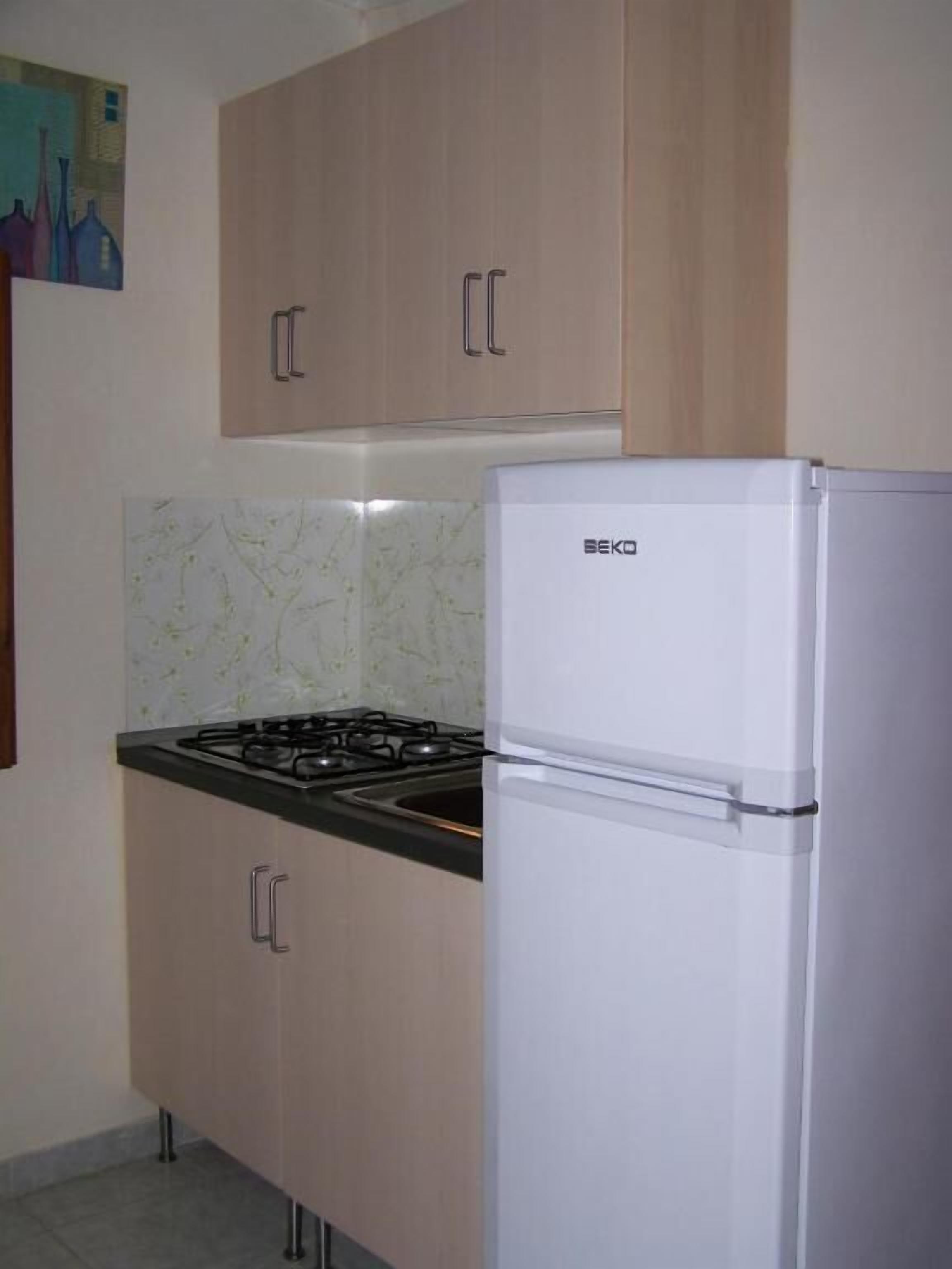 A kitchen with wooden cabinets, a gas stove, and a white refrigerator.