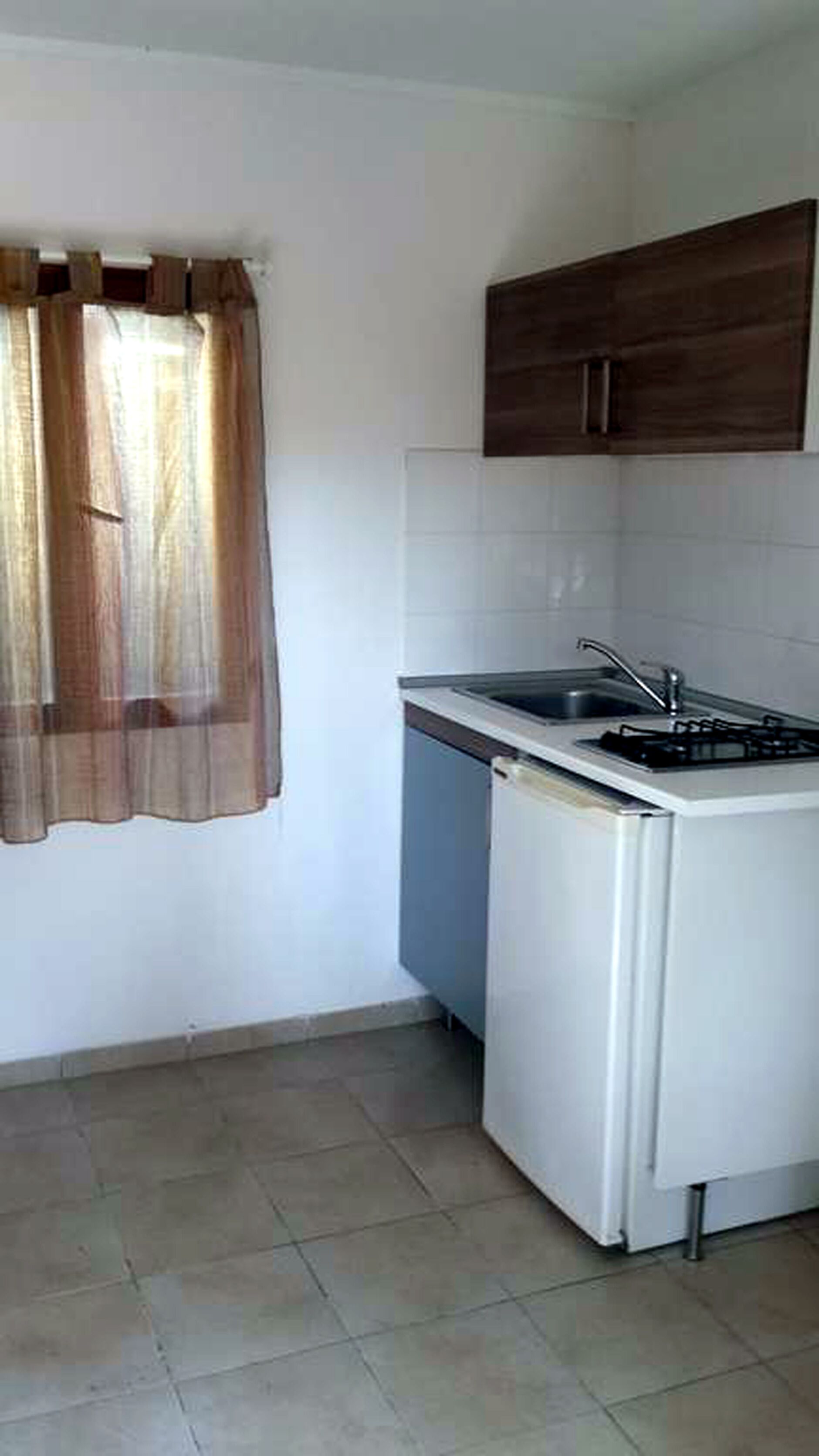 Una pequeña cocina con estufa, lavamanos y armarios.