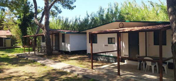 Una hilera de cabañas pequeñas de un solo piso, con un diseño sencillo, cada una con un porche pequeño y una ventana.